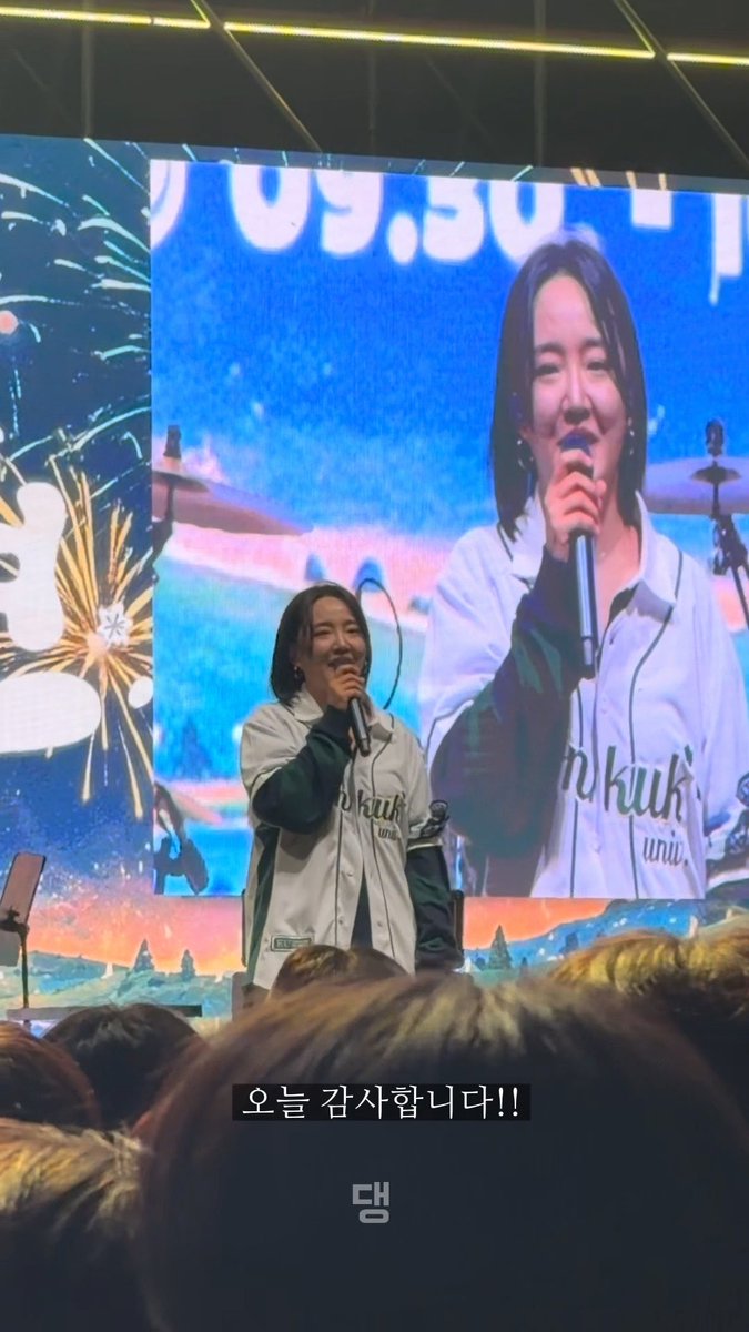 A young woman with short hair sings into a microphone on stage wearing a white and green jacket, with Korean text '오늘 감사합니다!!' (Thank you today!!) displayed below.