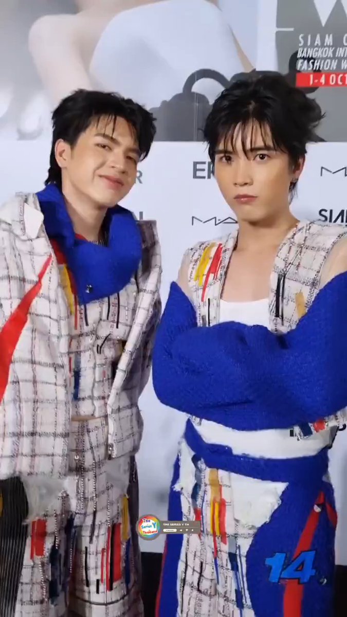 Two young men, identified as the Thai celebrity duo "พาย-กอล์ฟ" (Pie and Golf), pose together at the Bangkok International Fashion Week 2026 (BIFW26) at Siam Center, wearing matching colorful plaid suits with bold blue knit accents. The backdrop displays event branding including "SIAM," "BANGKOK INTERNATIONAL FASHION WEEK," "1-4 OCT," "MAC," and "ER," aligning with the post's #SiamCenterBIFW2026xPIEGOLF promotion.