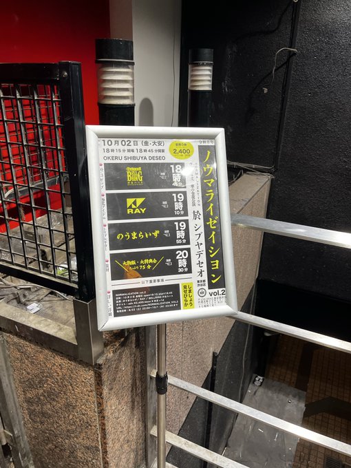 A sign outside a venue advertising a 'NOW LIVE SESSION vol.2' event on October 2nd at Oksar Festival Hall (Oksar Shibuya DESEO), featuring performances by BUZZ, RAY, and 'のうまいず'.