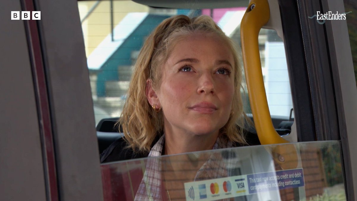 A blonde woman sits in the back of a taxi, gazing thoughtfully out the window, with payment signs visible on the glass. The "BBC" and "EastEnders" logos appear in the top corners, signaling her arrival on the show tomorrow at 7:30pm on BBC One and BBC iPlayer.