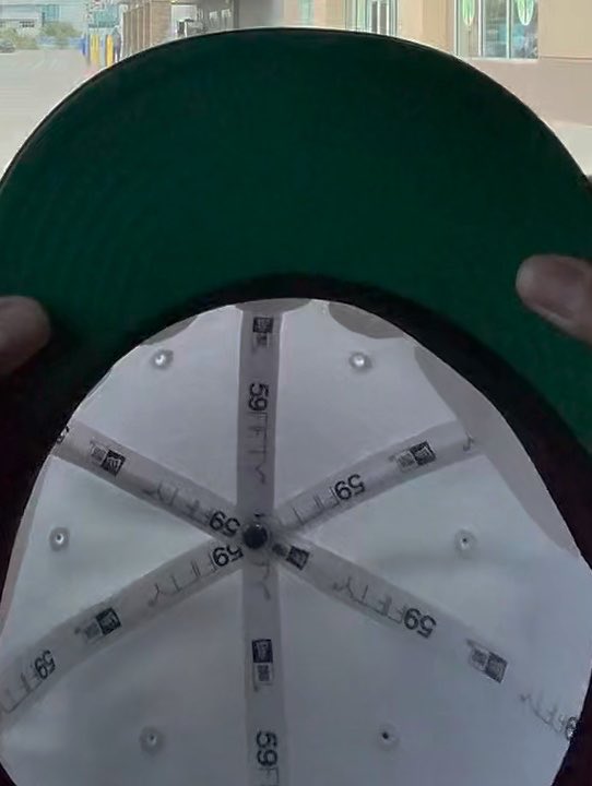 A close-up of the underside of a 59FIFTY New Era baseball cap showing the green brim and white interior panels.