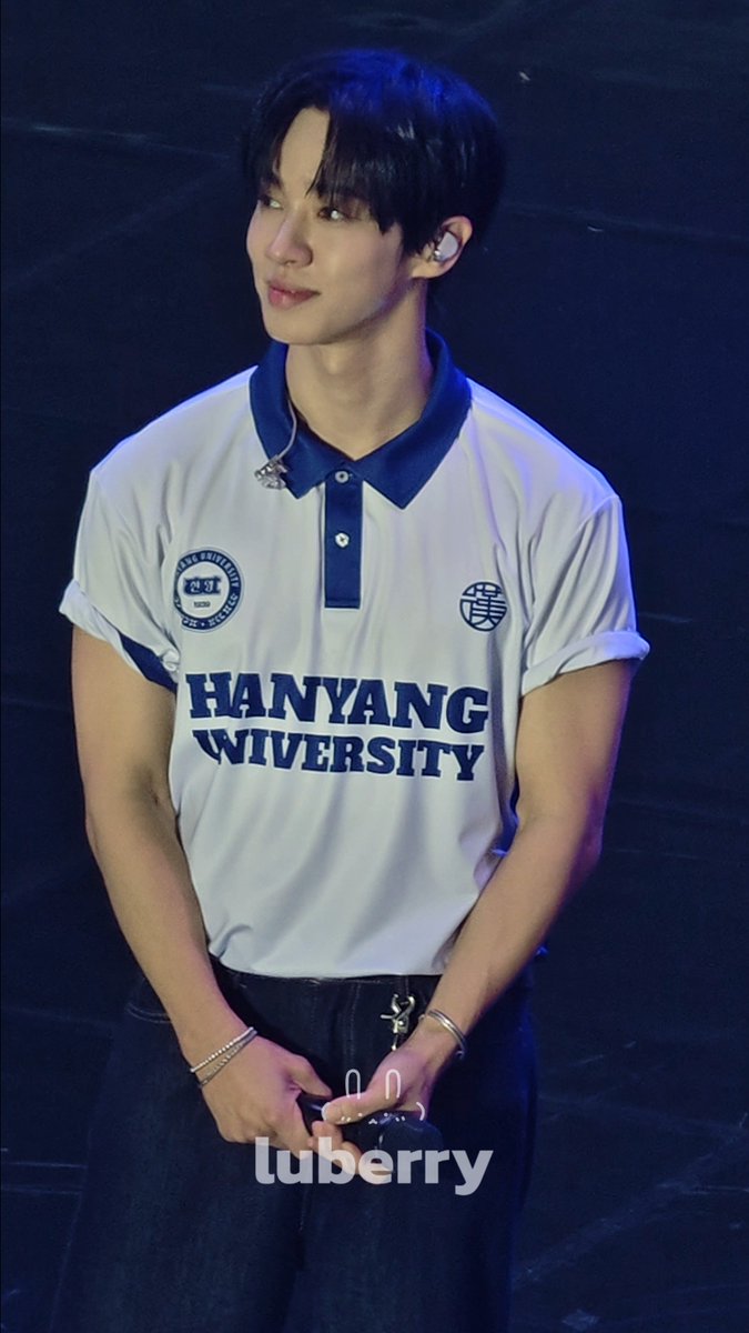 A young man wearing a white 'HANYANG UNIVERSITY' polo shirt performs on stage with an in-ear monitor and a 'luberry' watermark visible.