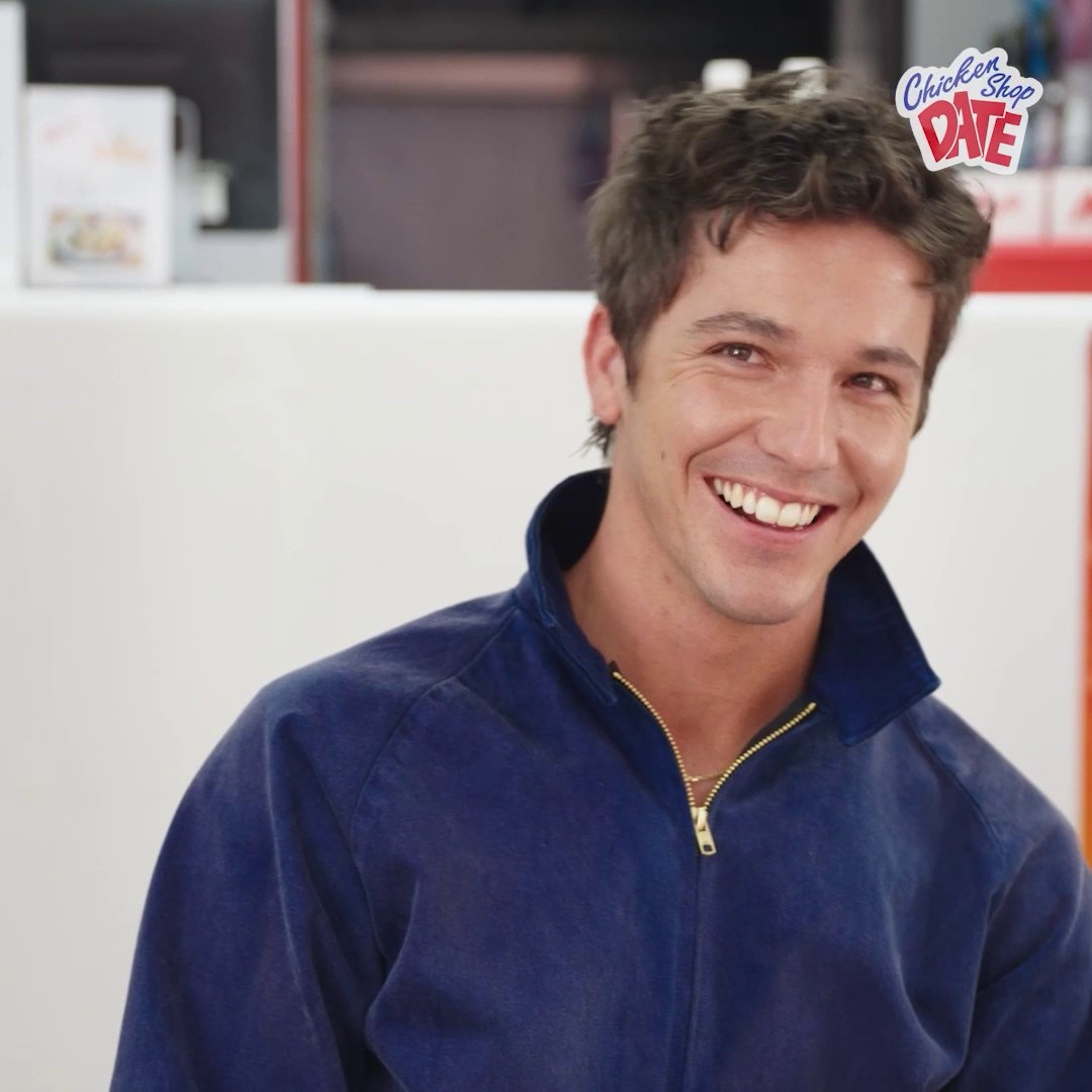 A smiling young man in a navy quarter-zip pullover appears in a brightly lit setting, with the "Chicken Shop Date" logo in the top right corner. The image promotes the latest guest appearance by the role model on Amelia Dimoldenberg's popular interview show, now streaming on Netflix.