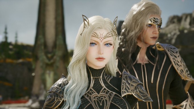 Two elven characters in ornate armor and circlets stand in an outdoor setting, with the silver-haired female in front and a male figure behind her.