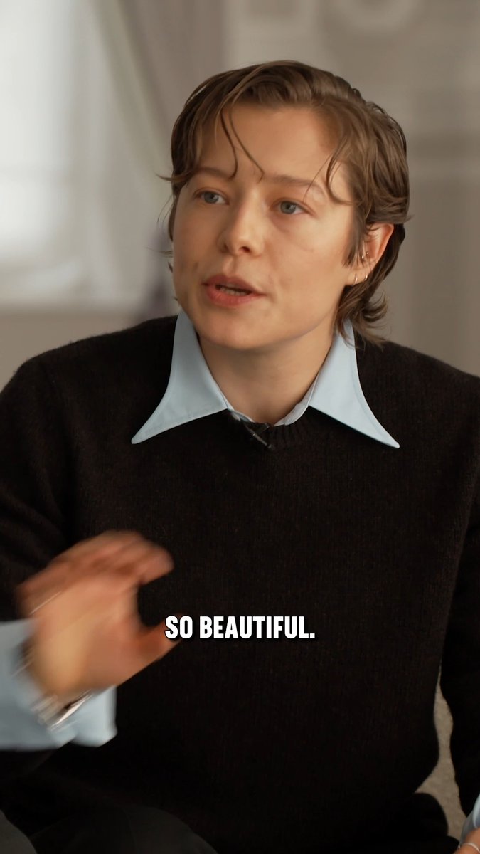 A young man with wavy brown hair wearing a black sweater over a light blue collared shirt speaks while gesturing, with the caption 'SO BEAUTIFUL.' displayed at the bottom.
