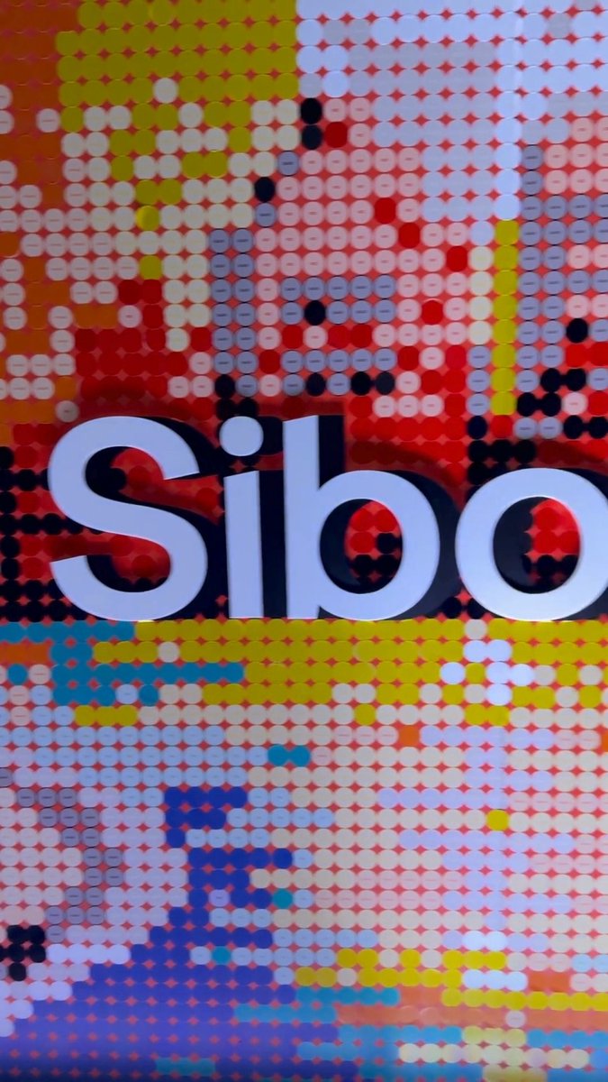 A close-up of a perforated display or banner featuring the word "Silo" in large white letters against a pixelated red, yellow, and blue pattern.
