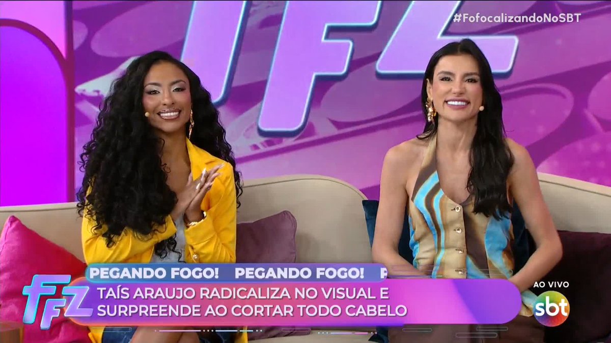 A live broadcast from 'FofocalizandoNoSBT' on the SBT network shows two smiling women on a pink set, with a news ticker reading 'PEGANDO FOGO! TAÍS ARAUJO RADICALIZA' NO VISUAL E SURPREENDE AO CORTAR TODO CABELO'.