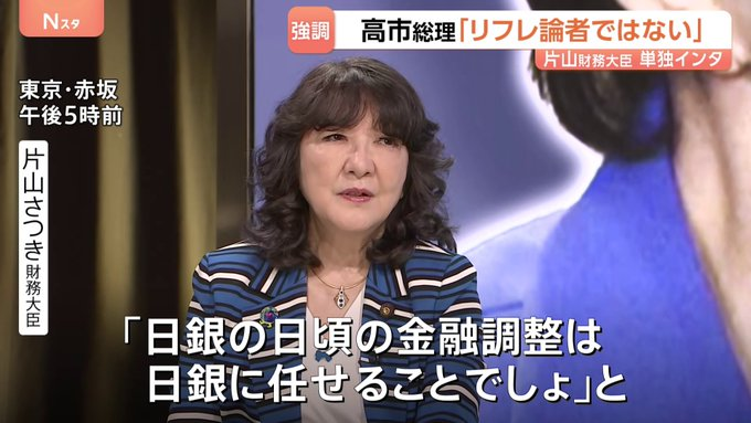 A Japanese news broadcast featuring a woman in a striped jacket, with on-screen text reading '高市総理「リフレ論者ではない」' (PM Takaichi 'I am not a reflationist') and a quote '日銀の目頃の金融調整は日銀に任せることでしょう' (The day-to-day monetary adjustments should be left to the Bank of Japan).