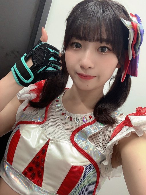 A young woman with dark hair poses wearing a colorful red, white, and iridescent stage costume with a matching glove and hair accessory.
