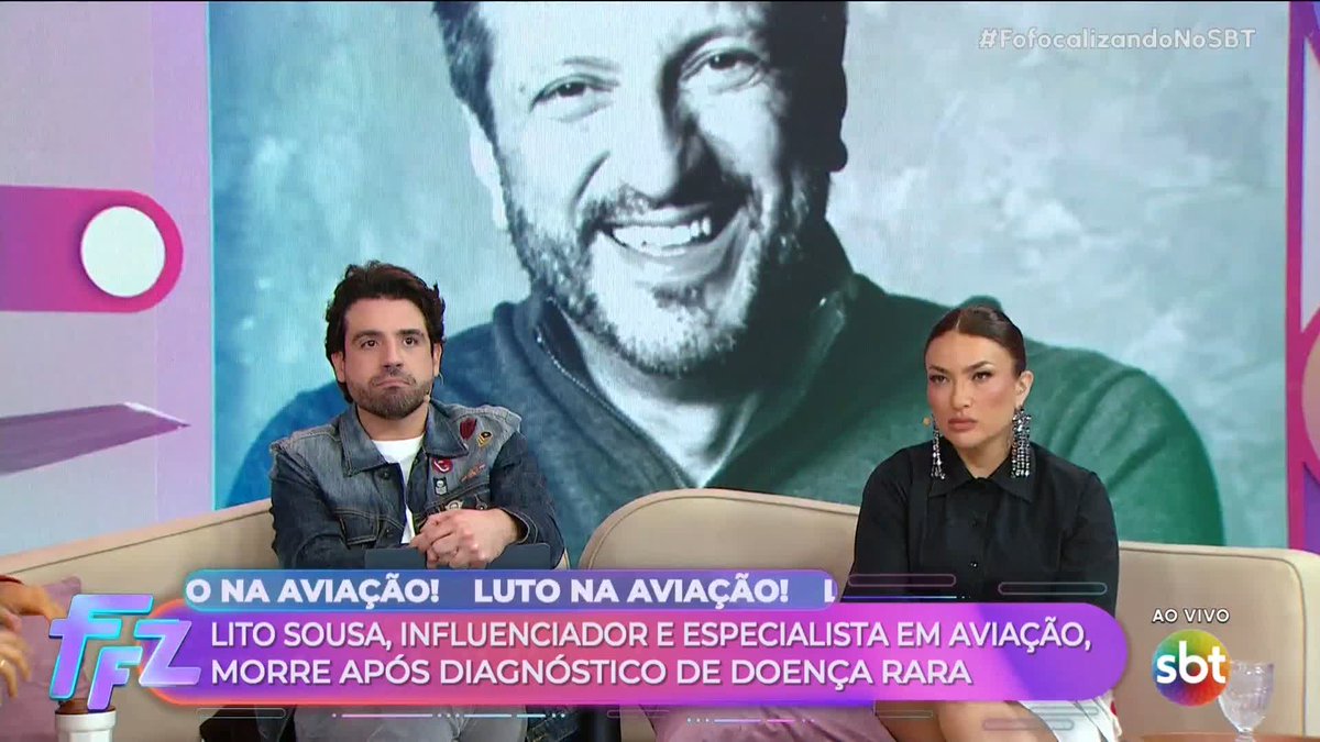 Brazilian SBT television broadcast (#FofocalizandoNoSBT) showing two hosts sitting on a couch with a large portrait of a man behind them; chyron states 'O NA AVIAÇÃO! LUTO NA AVIAÇÃO! LITO SOUSA, INFLUENCIADOR E ESPECIALISTA EM AVIAÇÃO, MORRE APÓS DIAGNÓSTICO DE DOENÇA RARA.'
