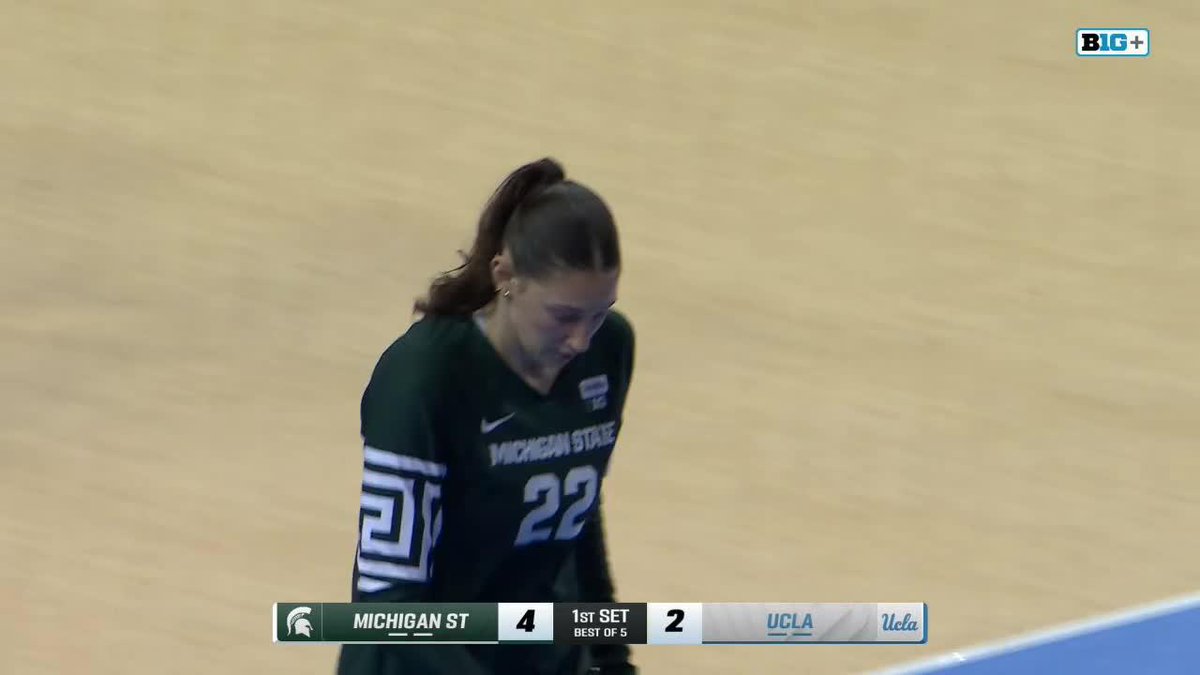A female Michigan State volleyball player wearing jersey #22 on the court, with a scoreboard showing Michigan St 4, UCLA 2 in the 1st set on the Big+ broadcast.
