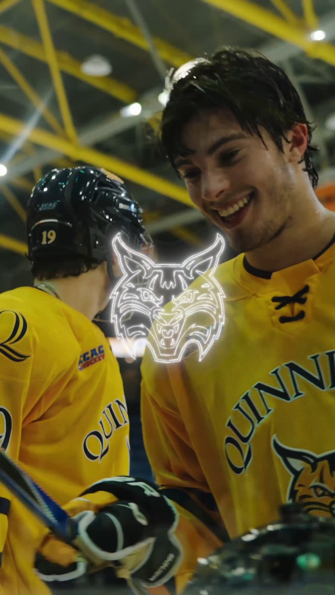 Two ice hockey players in yellow 'QUINN' jerseys are smiling and interacting, with one wearing helmet number 19, and a glowing wolf logo overlay between them.