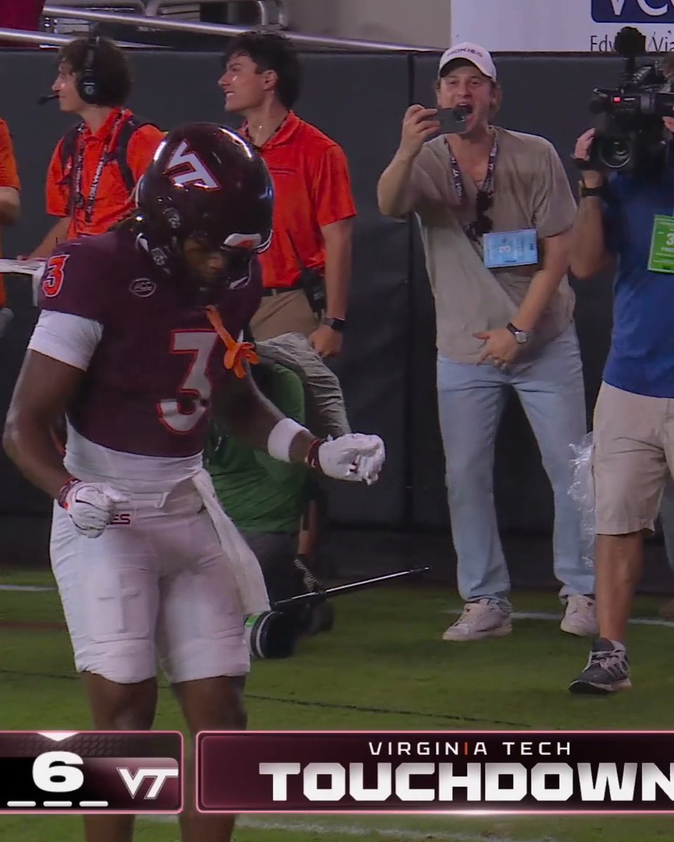 A sports broadcast showing a Virginia Tech football player (#3) in a maroon jersey celebrating a touchdown, with the ticker reading "VIRGINIA TECH TOUCHDOWN".