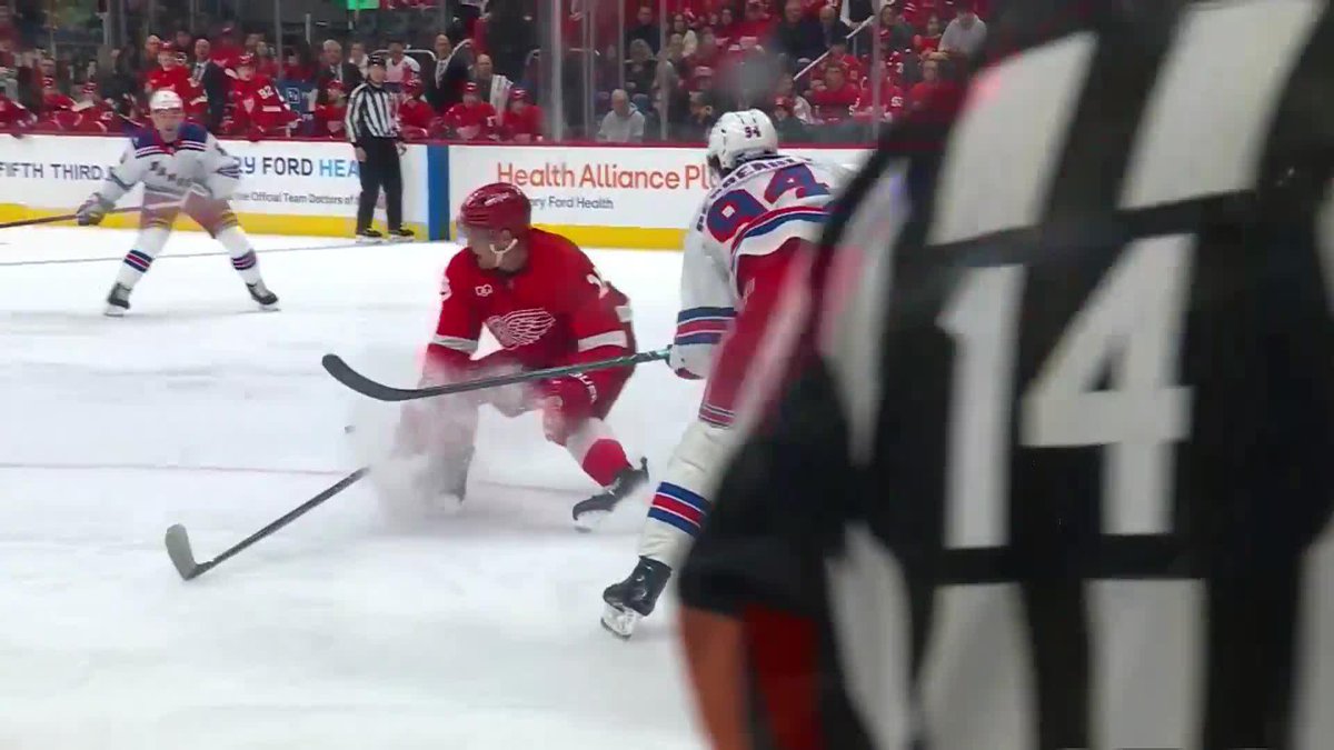 The photo shows a Detroit Red Wings player in a red jersey battling for the puck against a Rangers player wearing number 94, likely Gabe Perreault, during an NHL game with visible "Health Alliance" and "FIFTH THIRD" advertisements on the boards.

The image relates to the post by showcasing Perreault (#94) in active gameplay, highlighting the strong performance that Biz and Ace are reportedly enjoying from him.