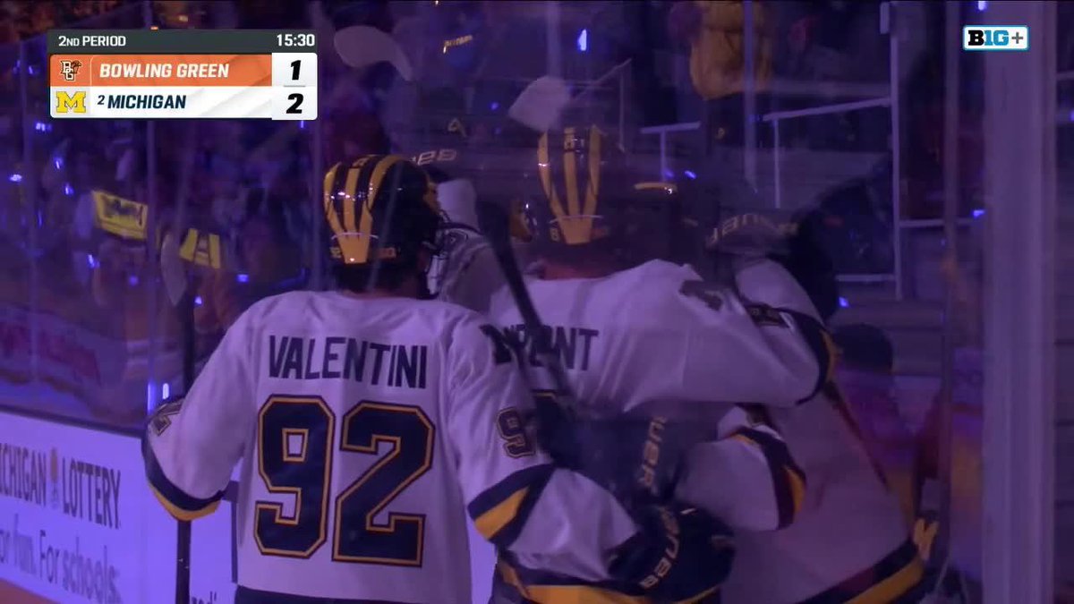 Michigan hockey players, including #92 Valentini and teammate DuPont, celebrate near the boards after a goal scored by McKinney, giving Michigan a 2-1 lead over Bowling Green with 15:30 left in the 2nd period.