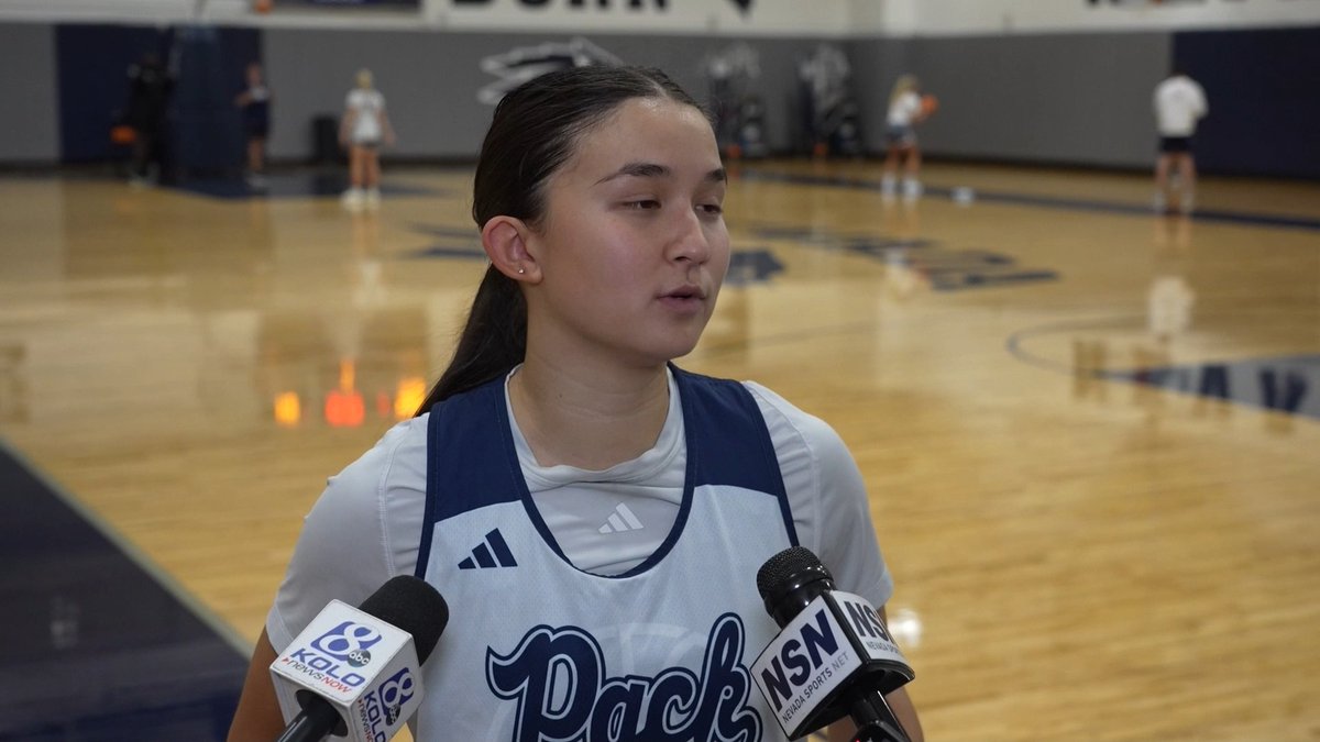 A young female athlete in a white and navy 'Pack' jersey being interviewed at a basketball practice facility, with KOLO and NSN microphones visible.