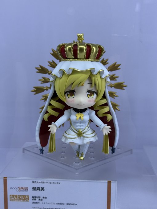 A Nendoroid figure of a blonde character wearing a white dress and a gold crown with red jewels is displayed in its packaging box.