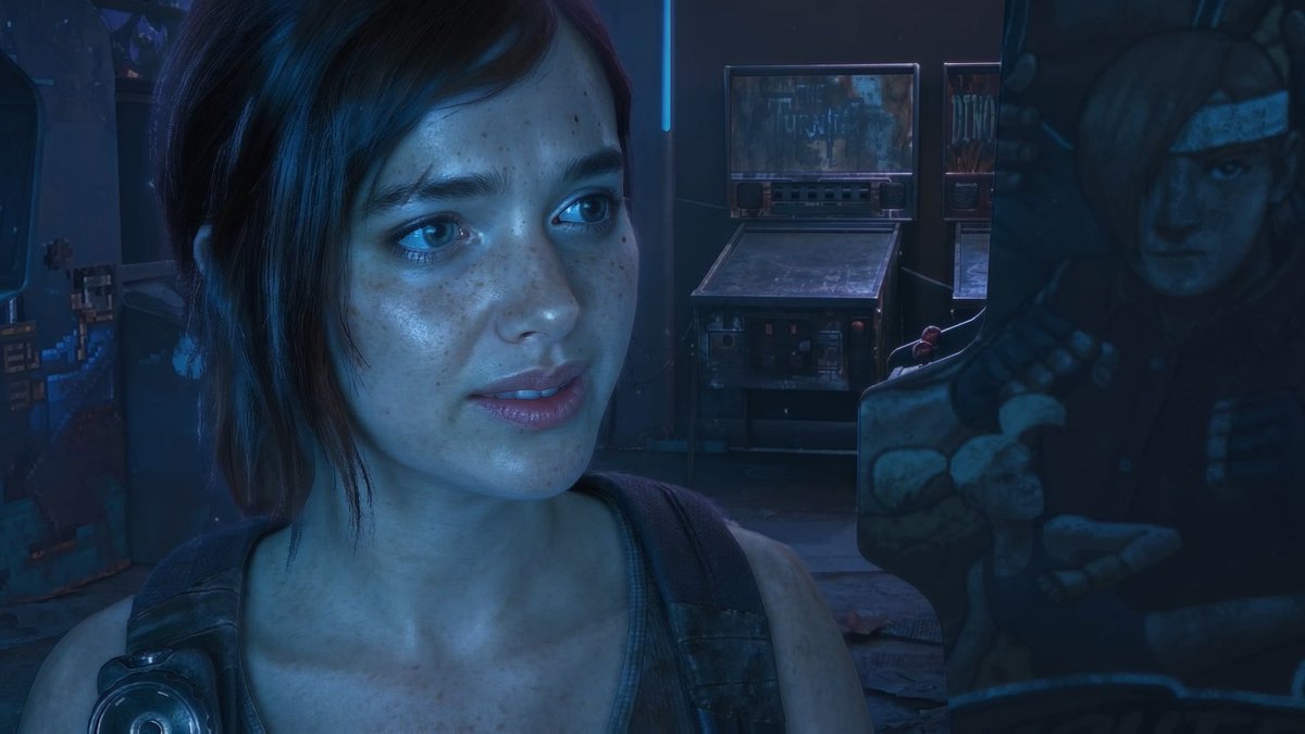 A young woman with short brown hair and freckles stands in a dimly lit arcade, looking thoughtfully off-camera with the word "SHADOWS" visible on a pinball machine behind her. The scene captures a quiet moment from The Last of Us Part I's Left Behind DLC, where players explore Ellie's backstory and bond with her before meeting Joel, all enhanced by DLSS5 photorealism on an RTX4070.