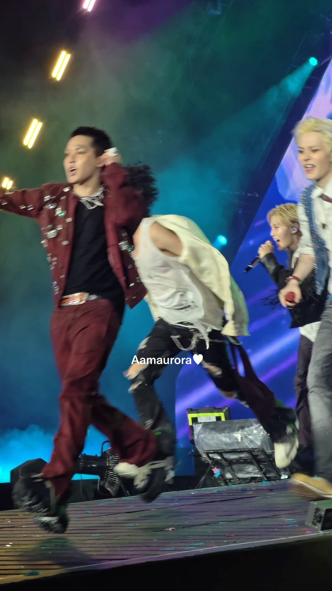 Performers on a brightly lit stage dance energetically, with one wearing a burgundy jacket and another in a white vest; a watermark reads "Aamauora♥".
