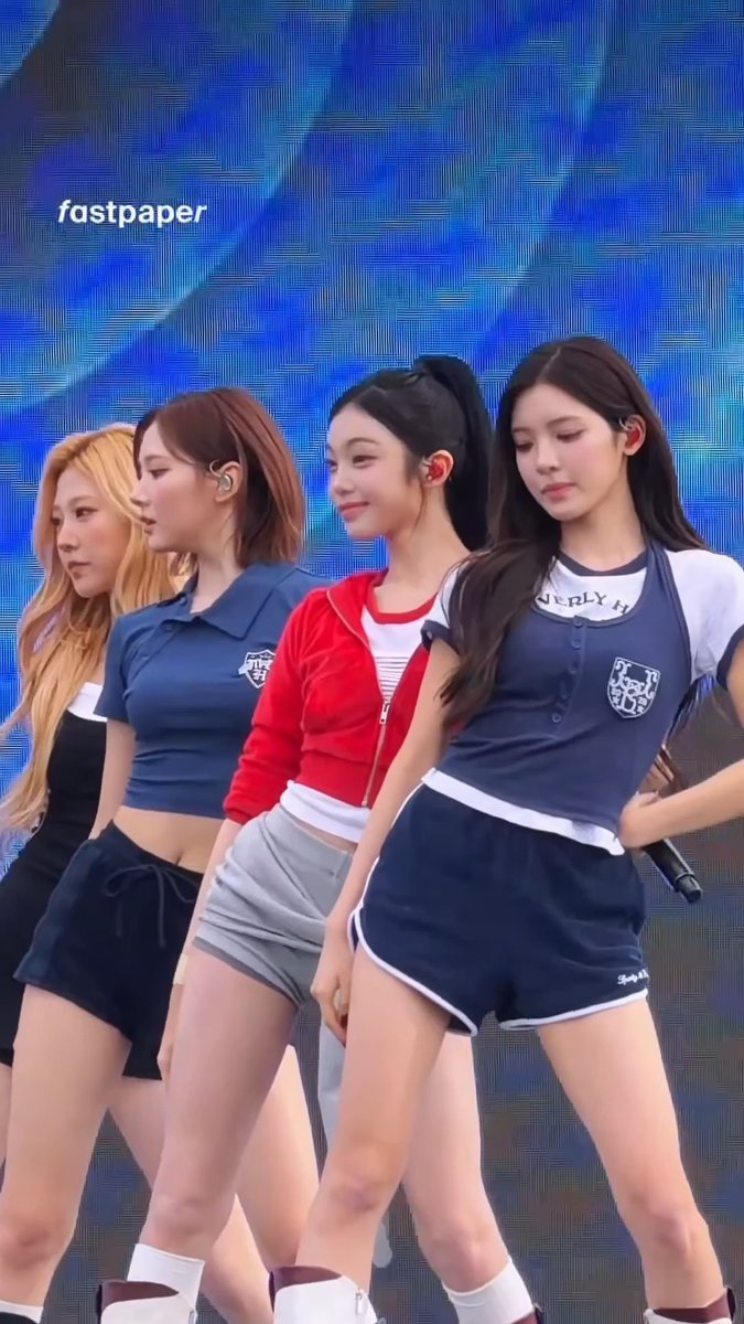 Four young female performers in coordinated athletic-style outfits (navy, red, and white tops with matching shorts) pose together on stage, with "fastpaper" watermark visible in the corner, appearing to be members of the K-pop group Hearts2Hearts (하츠투하츠) specifically JIWOO, IAN, YUHA, and STELLA as tagged in the post.