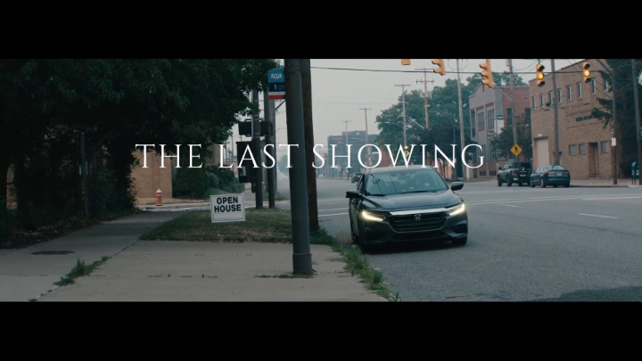 A cinematic shot of a dark car on a street with the text overlay 'THE LAST SHOWING' and a sign for an 'OPEN HOUSE' visible on the sidewalk.