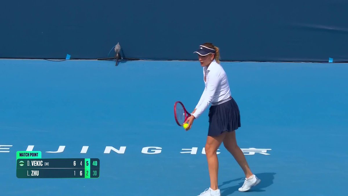 Tennis player D. Vekic prepares to serve at match point against L. Zhu, with the scoreboard showing 6-4, 5-2 (40-30) during a BEIJING match.