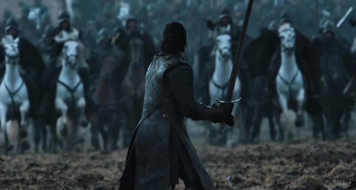 A dark-haired warrior in a long leather coat holds his sword ready as he faces an army of mounted soldiers on horseback in a bleak battlefield.