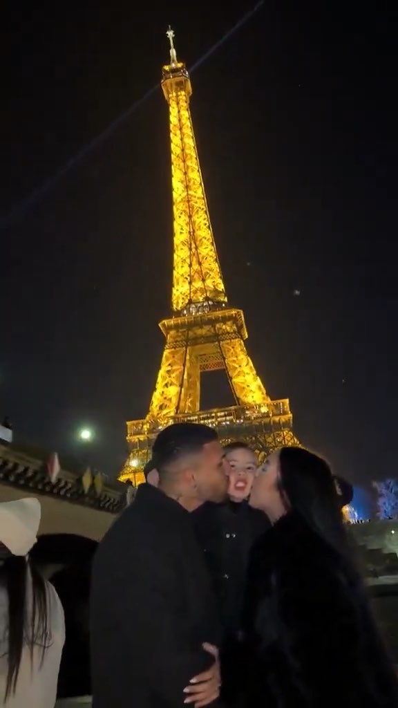 A family of three shares sweet kisses on the cheeks in front of the illuminated Eiffel Tower at night, capturing a tender moment that perfectly reflects the post's message of trust, timing, and pure love.