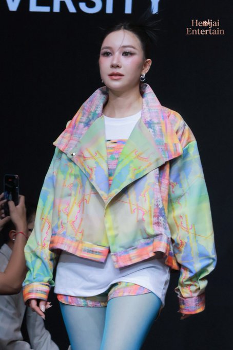 จูน ณัณณิริณ สวมเสื้อแจ็คเก็ตลายสีพาสเทลหลากสีจัดจ้านร่วมงาน Bangkok International Fashion Week 2026 (BIFW2026) ที่ SIAM CENTER โดยมีโลโก้ JUNE และข้อความ "IVERSITY" ปรากฏบนฉากหลัง.