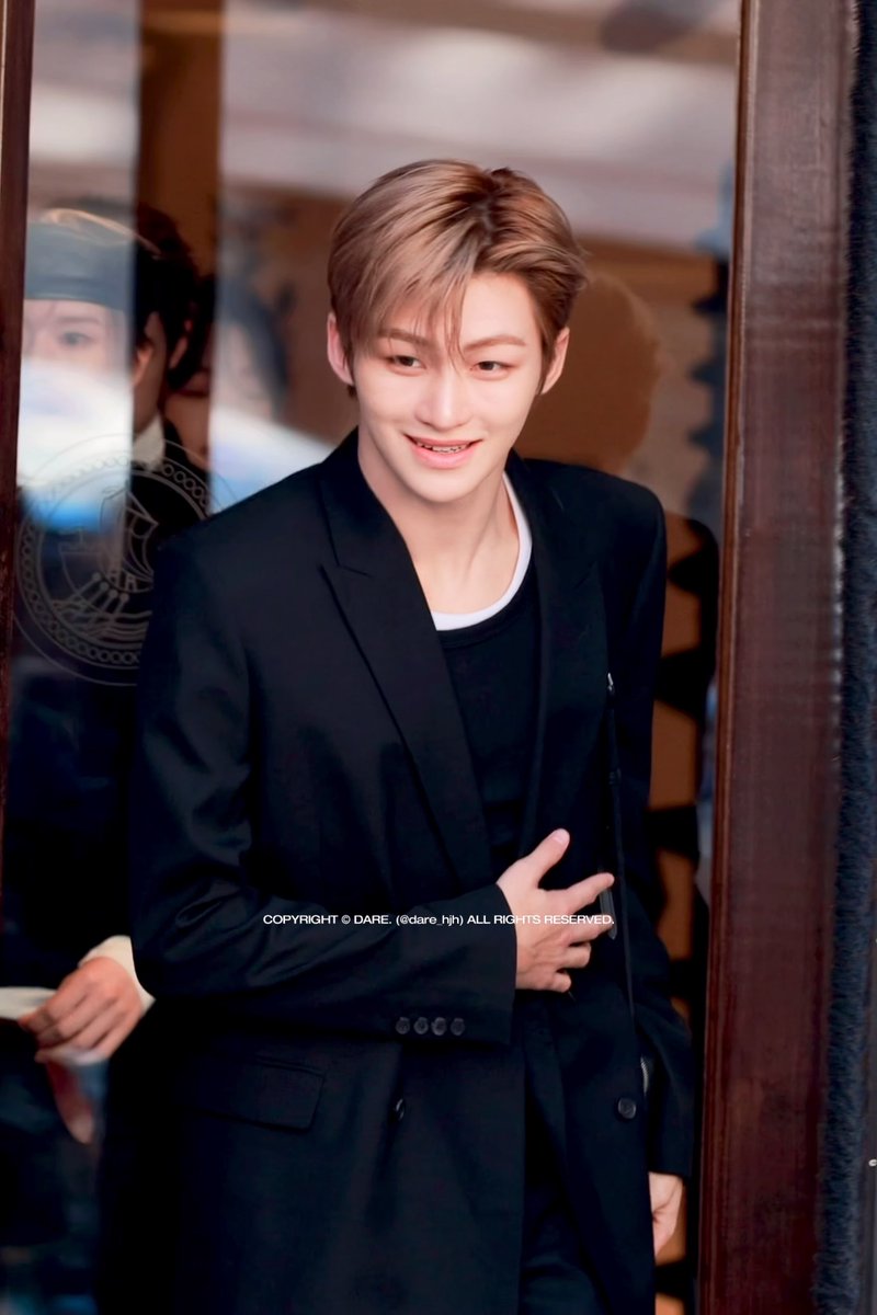 A portrait of a young man with light brown hair wearing a black blazer over a white shirt, smiling with a copyright watermark 'COPYRIGHT © DARE. (@dare_hj) ALL RIGHTS RESERVED' across the middle.
