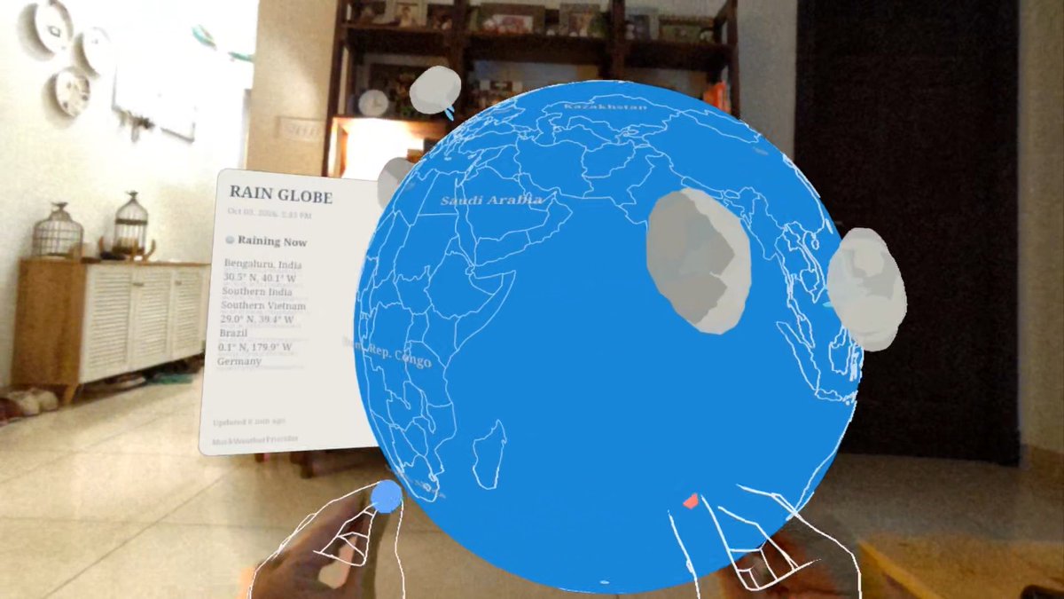 An augmented reality view of a 'RAIN GLOBE' showing weather information for Bengaluru, India, Southern Vietnam, and Brazil, superimposed on a blue globe in a living room setting.