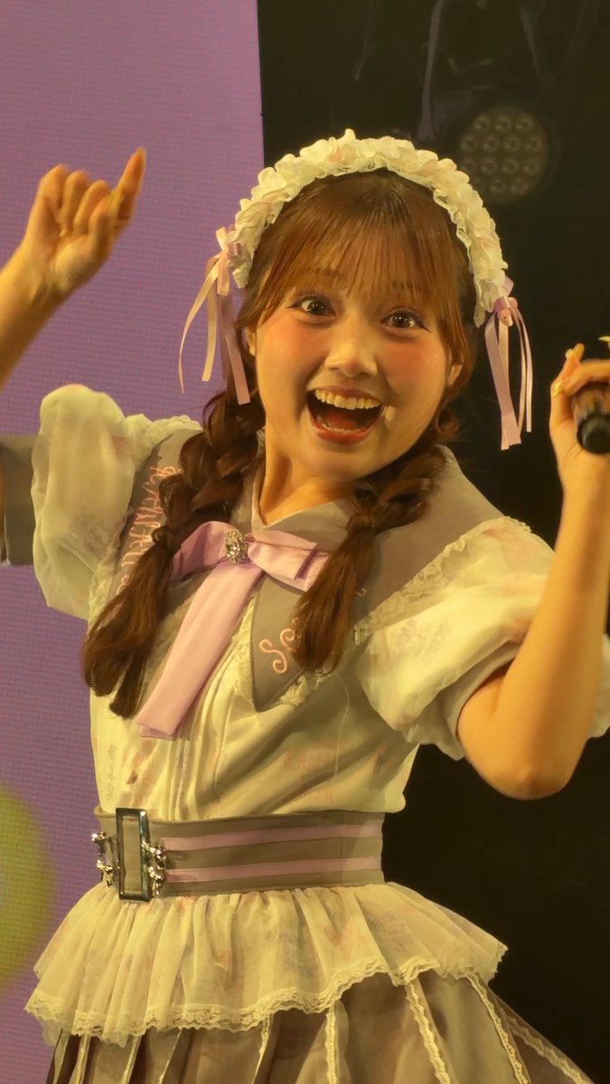 A performer on stage beams excitedly at the camera with her hand raised, wearing a frilly pastel maid-style outfit with a ruffled headband and braided pigtails, identified in the post as Ichimon-chan (門倉彩花) during a Kawa Lab South event.
