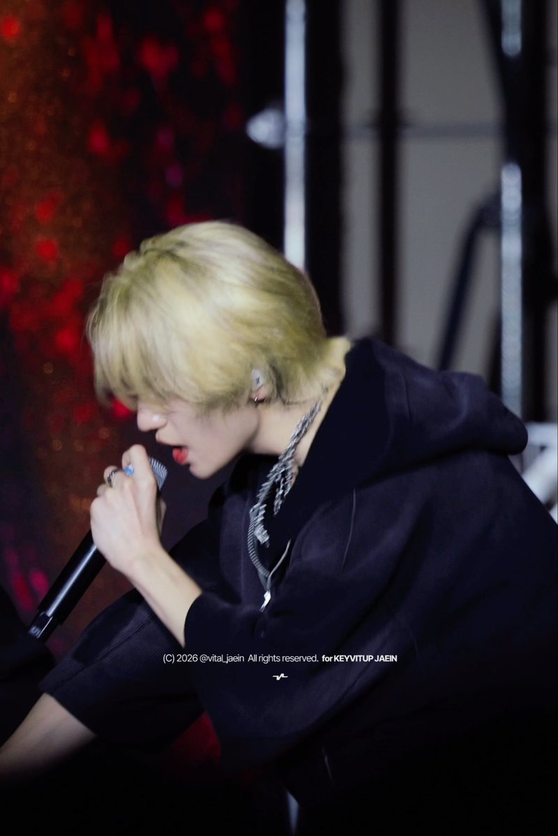 A blonde performer sings into a microphone on stage, with copyright text reading '(C) 2026 @vital_jaein All rights reserved. for KEYVITUP JAEIN'.