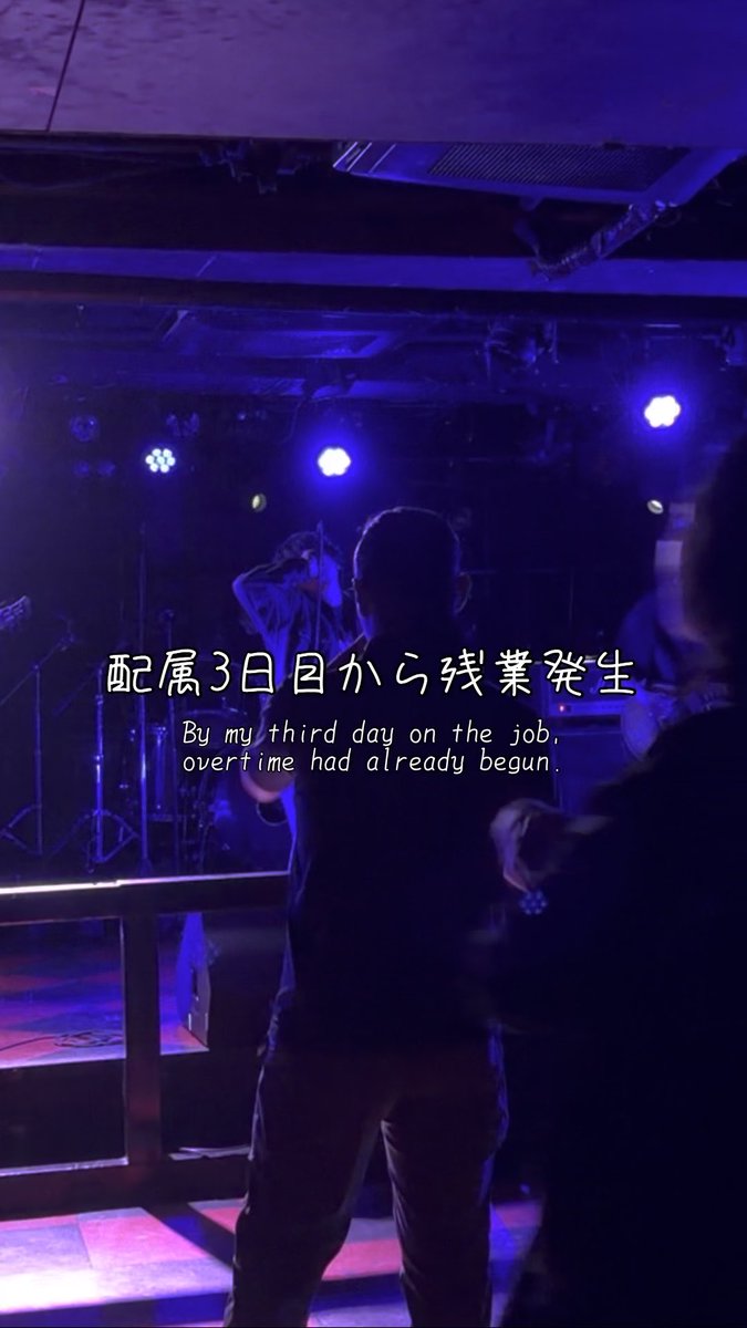 A person stands on a stage under blue lighting with Japanese and English text overlaid reading "配属3日目から残業発生 / By my third day on the job, overtime had already begun."