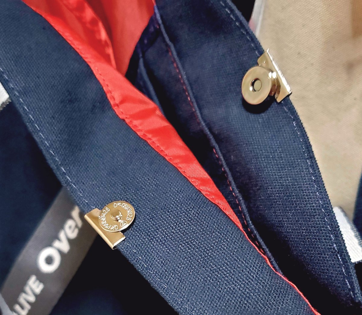 72_matsu_'s tweet photo. めちゃつえーライブのトートバッグ、留め具とかついてないから口が開きっぱで荷物が飛び出てきそうだったのでSeriaでマグネットホックなるものを買って付けてみた　ヘリ留めタイプだから針も糸も使わず付けれて良いね
バッグが大きいから両脇が閉まってないけど無いよりはマシって感じ https://t.co/FAHGtttwfk