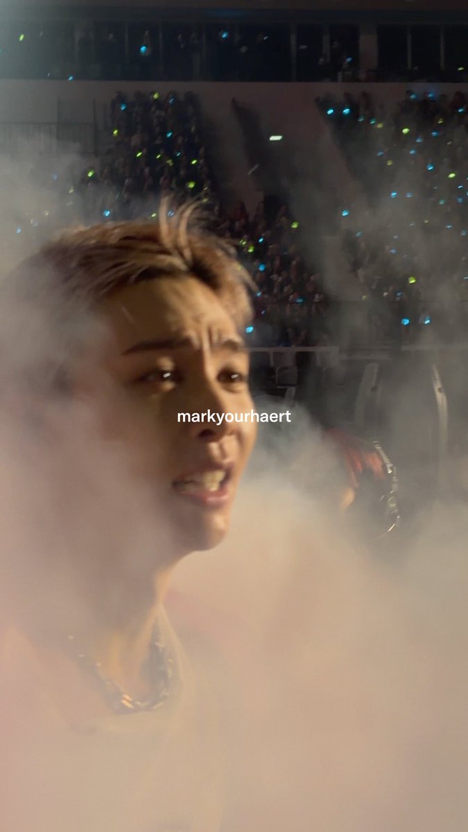 Taeyong is seen up close on stage amid heavy fog and colorful light sticks from the audience, with the watermark "markyourhaert" visible across the image. The scene captures an intense, atmospheric moment from NCT 127's *The Red Line* concert in Jakarta.