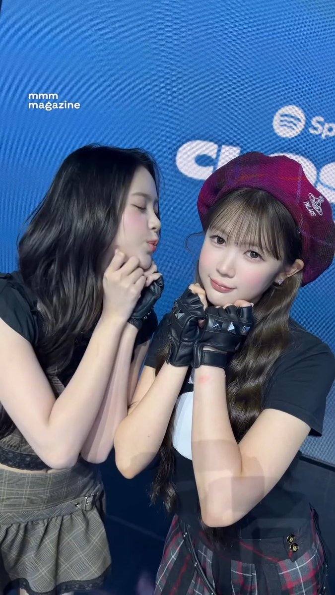 Two young women pose together in edgy outfits with black studded gloves, one wearing a red Vivienne Westwood hat, with 'mmm magazine' text visible on the blue backdrop.