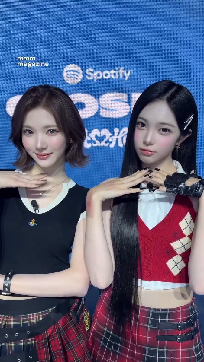 Two young women with long hair pose with their hands together at a Spotify event, with 'mmm magazine' and Korean text visible on the blue backdrop behind them.