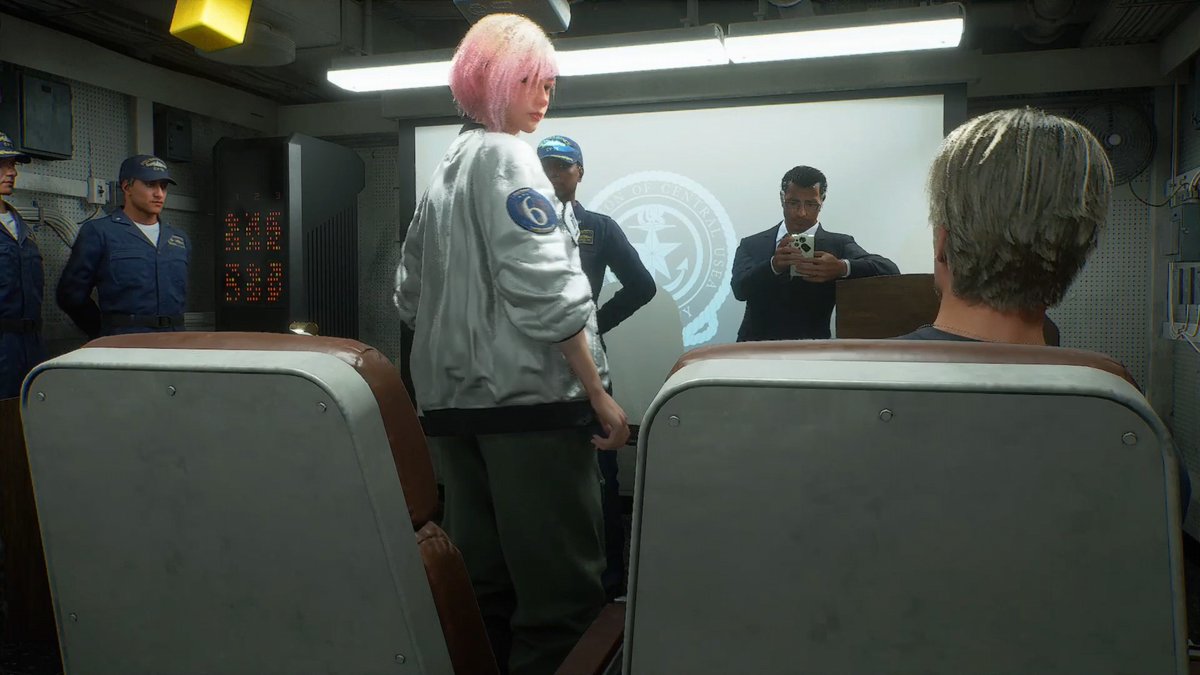 A pink-haired character in a white jacket with "6" on it stands inside a dimly lit room featuring a digital timer reading "00:25:00," surrounded by seated onlookers and military personnel as a suited man takes notes near a "DEPARTMENT OF CENTRAL INTELLIGENCE" emblem projected on the wall. The scene captures a tense moment, likely a quick-time event during the movie sequence mentioned, with the player's seated position prompting Tasha's reaction and a mischievous companion refusing to stand up.