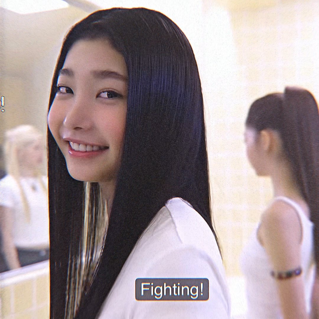 A young woman with long straight black hair smiles brightly over her shoulder, accompanied by the subtitle 'Fighting!'.
