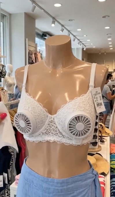 A mannequin in a retail store displays a white lace bra equipped with two small built-in fans in the cups, with a visible price tag of "M" size. This quirky "innovation" humorously illustrates the post's joke about China's extreme take on women's comfort—turning an undergarment into a personal cooling system.