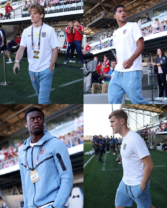 Four members of the England national football team, known as the Three Lions, are seen arriving at the stadium wearing their official white and light blue Nike kits with lanyards marked "207," preparing for an upcoming match.