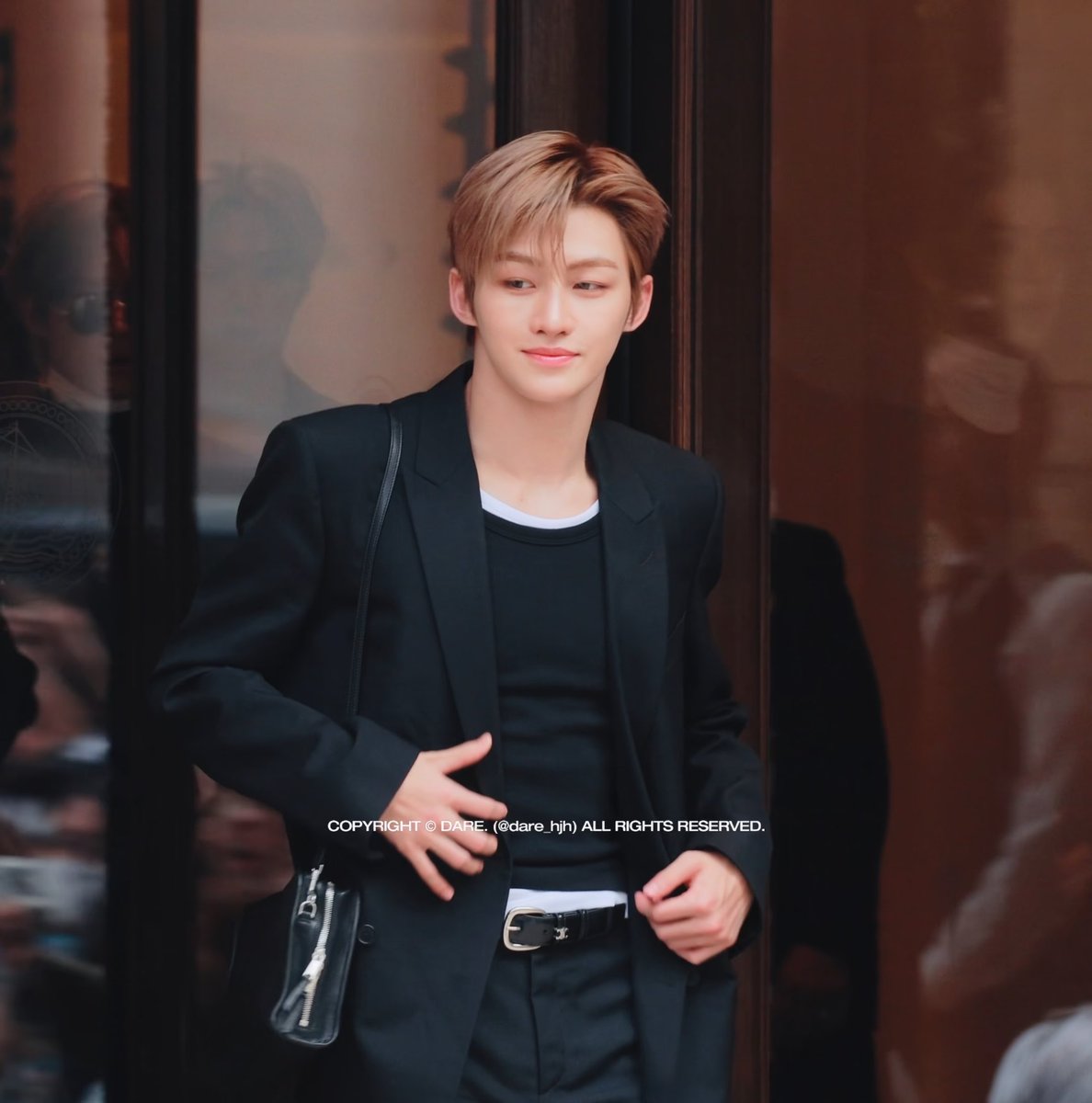 A young man with brown hair in a black suit and black t-shirt standing in a doorway, with copyright text 'COPYRIGHT © DARE. (@dare_hjh) ALL RIGHTS RESERVED.'