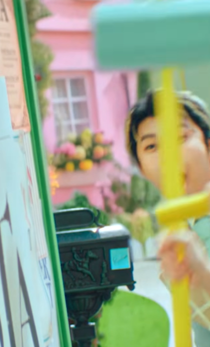 wattan5's tweet photo. #ミセスPOPS のMV #ミセス共犯 のMV考察です。
今までの #MrsGREENAPPLE の考察のようにMVの中の事実だけから考察していきます。
まず起床は起承転結の起。(@daystarter)さんかな？
おじさんが国際郵便を届けるのですが、間違っていたらごめんなさい。切手デザインが多分イラストレーター笠井由雅子さんかな？　と思いました。タッチが #金木和也 のジャケットデザインと似ていたので。
ではこの手紙は誰から届いたのでしょうか？「To dearest Mrs.GREENAPPLE」 と書かれています。
どこかアメリカのコメディドラマのような街。大森さんは 'A' と書かれた家から出てきます。　

何故'A'なのか違和感です。他の家にも棟なら表示されるはず。ＯやＭならまだしも。

そして「催し」でもあったまた新聞紙を持っている人がいます。
「催し」でも調べたらとんでもない事が書かれていましたが、今回も調べました。調べるの大変笑

 「More than a festival - a stronger Riverton」
（祭り以上のもの。リバートンを、もっと強い街へ）

という感じです。　ここまでなら違和感がないのですが、
その後の催しの掲示板に、

「A day filled with - good music, good food, great people and a FISH STORY or two.」
（良い音楽、おいしい食事、素晴らしい人たち、そして1つか2つの大袈裟な嘘に満ちた一日）

と、そんなこの明るい街を全否定し、しかも笑いながら後でハンマーで殴っています。やな世界。これも違和感。
違和感は続きます。　まず建物全体が、建物を色を左右対称に半分ずつ色を分けています。
シンメトリーというやつです。　また人間もシンメトリーに寄り添っています。
双子のように同じ動きをする２人がダンサー以外に６組も。
警官が分かりやすいですが、それ以外にもめちゃくちゃいます。

なのにシンメトリーではない人達もいます。　それは Mrs.GREENAPPLEです。
他にもいますがそれは後ほど。

「共犯」の歌詞を見ればみるほど、聴けば聴くほどこの歌詞とメロディに合うのは、
それこそ「ア・ポステリオリ」のようなＭＶが似合いそう。
それをあえてメロディもＭＶも見た目をPOPSに仕上げきっているのは狂気すら感じます。
ただ、MVは狂気じみた違和感がたくさんあるということ。
それをただ目を瞑って過ごしているのなら、
誰もが共犯だと思う。
大森さんと馬をかついでいる郵便配達員のおじさんは、大森さんが見ていない時だけ苦しそうにしている。
大森さんが振り返ったら愛想笑いをし、また顔が戻ったらまた疲れている。

知ってて知らないふりしている世界
シンメトリーだと思っていたのは、アシンメトリーの世界

それは別に大森さんだけじゃない。
この世界が突然終わり、次は同じ演者が同じ自分を見ているアシンメトリーの世界観に変わります。

観客の後ろには 'STAGE B' と書かれています。

これだけじゃ違和感はないですが、大森さんは 'A' から出てきました。
無関心にただ見ていた大森さんですが、

「素晴らしさを分かってはいるのに　この世界に生まれたらもう共犯」

と口ずさみ立ち上がる。次に若井さん藤澤さんが立ち上がり、次に１人だけステージでもステージ外でも同じ服の女の子が共感する。
共犯という名のアシンメトリーな自分自身を’共生’として受け入れたのだと思います。
それがMrs.GREENAPPLEの大森元貴だとしても、というか「GOOD DAY」という楽曲をフェーズ３の頭にリリースしたのも
色々な事を腹をくくったのかな？　二人も。そうしたのもそうなったのも自分自身だけど、
僕も二人も、もう腹をくくったから、聴いている貴方たちも共犯なんですよと。

ならMVの最初に戻って、「To dearest Mrs.GREENAPPLE」は誰なのでしょうか？

JAM'S。

部屋から出ていく時、大森さんは手紙を見てうなずいている。わかった。わかってる。
最後にはこのアシンメトリーな世界を見ていたのは、様々な色も形も異なる宇宙人で、共感しています。

ただ、そのＵＦＯの室内には、全く意味のない 'C' と書かれています。

内から外へ出て行ってる。なら、'D'は？

実際には 'D' はあります。
それはこのMVを観てしまった外の世界の私たちです。
もう観てしまったからには、考察してしまったからには、もう共犯なんです。

最後に。

違和感のサラリーマン風男性がずっと背中に青い張り紙を15枚ほどつけて歩いています。
本人は知らなさそうなのですが、左右ずっと歩いて本人以外はみんな気づいています。

映画「バックトゥザフューチャー」でもあった「Kick Me!（蹴って！）」といういたずらかもしれません。
これに気づいたのはＡＢＣＤ全員なのに、あれだけわかりやすく見てるのに誰も背中の張り紙について話さない。

あんまり考えたくはないですが、もし本当に「Kick ME」なら、
いじめられているのに、手を差し伸べないのなら、それはもう貴方も共犯です。

MVでは、貼られているサラリーマンが、おばあさんに挨拶し、
おばあさんだけが気づいて張り紙を１枚はがしている。
よく見ると、おばあさんは驚いた場面もあります。

剥がした１枚をポストに貼り付けています。　その１枚はハンマーで叩いている若井さんの後ろのポストに。
ボケていますが、文字からいってあの言葉かもしれません。忘れないための「餅つき大会」とかのメモならいいな。

８番出口のように、困っている人がいたら、助けを求めている人がいたら見ぬフリはやめようねっていう。
言葉は毒にも薬にもなるけれど、薬だけ持ち歩きたいな。
アシンメトリーな自分自身にも共生して生きていく。
ただ、優しさも分け合ってこそ、見事に共犯です。

ミセスと共に共生して、運命共同体。素敵な共犯になりましょう。

以上、共犯考察でした！👀👀
