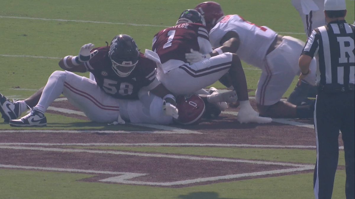 Mississippi State Bulldogs football players (numbers 58 and 1) tackling an Alabama Crimson Tide player near the goal line with a referee nearby