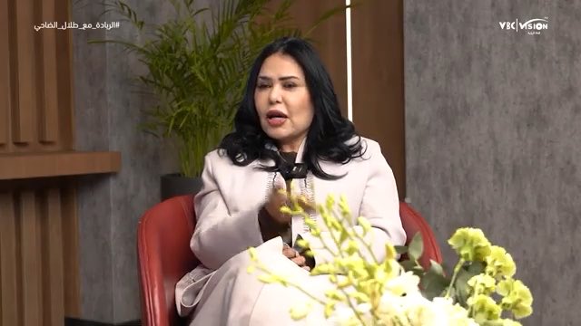 A video screenshot shows a woman with dark hair wearing a light pink blazer sitting in a red chair during an interview, gesturing with her hands, with a 'YBC VISION' logo in the top right corner and Arabic text '#الزواج_عند_الخليل_الحلبي' in the top left.