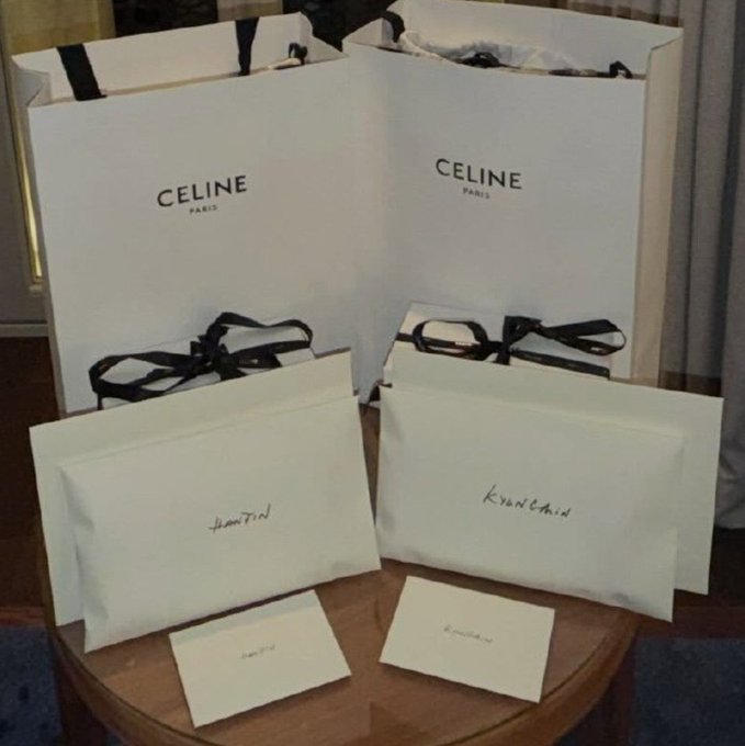 Two white CELINE Paris shopping bags with black ribbons sit on a wooden table alongside their matching envelopes and small cards, with a name handwritten in cursive on each—capturing the "asdfghjkl" reaction of being completely speechless over a high-end designer haul.