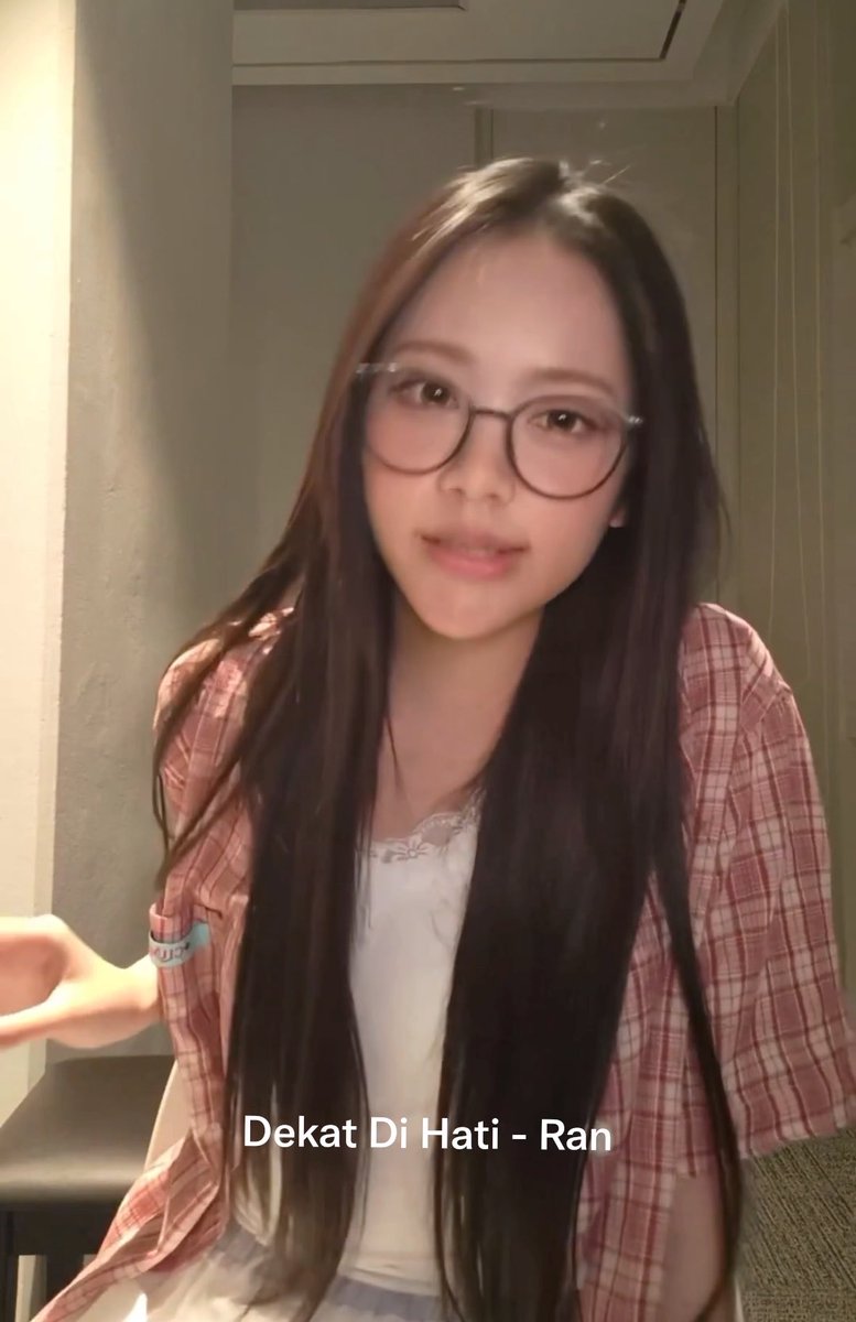 A young woman with long dark hair and round glasses performs a heartfelt cover of the Indonesian song "Dekat Di Hati" by Ran, as shown by the text overlay, sharing Indonesian jazz music with a Korean audience through her expressive singing.