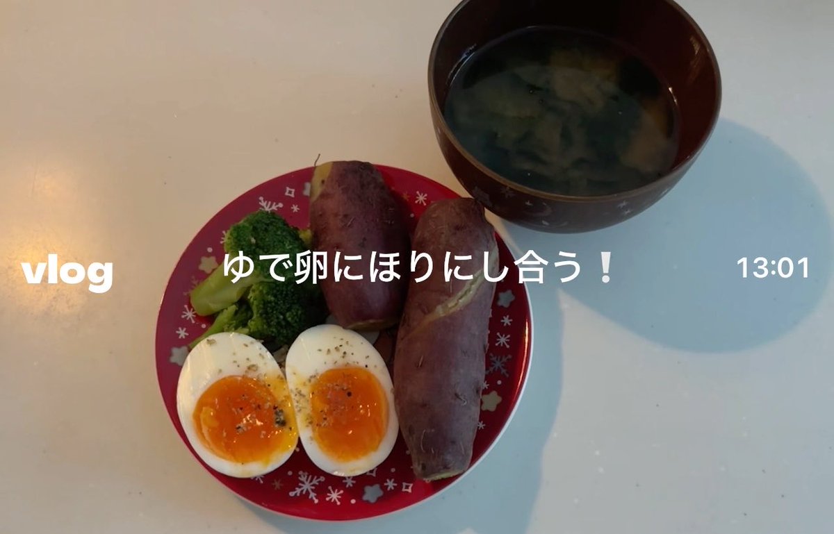 A vlog-style photo showing a meal of boiled sweet potatoes, broccoli, and a halved soft-boiled egg seasoned with pepper, served with miso soup. Text reads 'vlog ゆで卵にほりにし合う！ 13:01'.