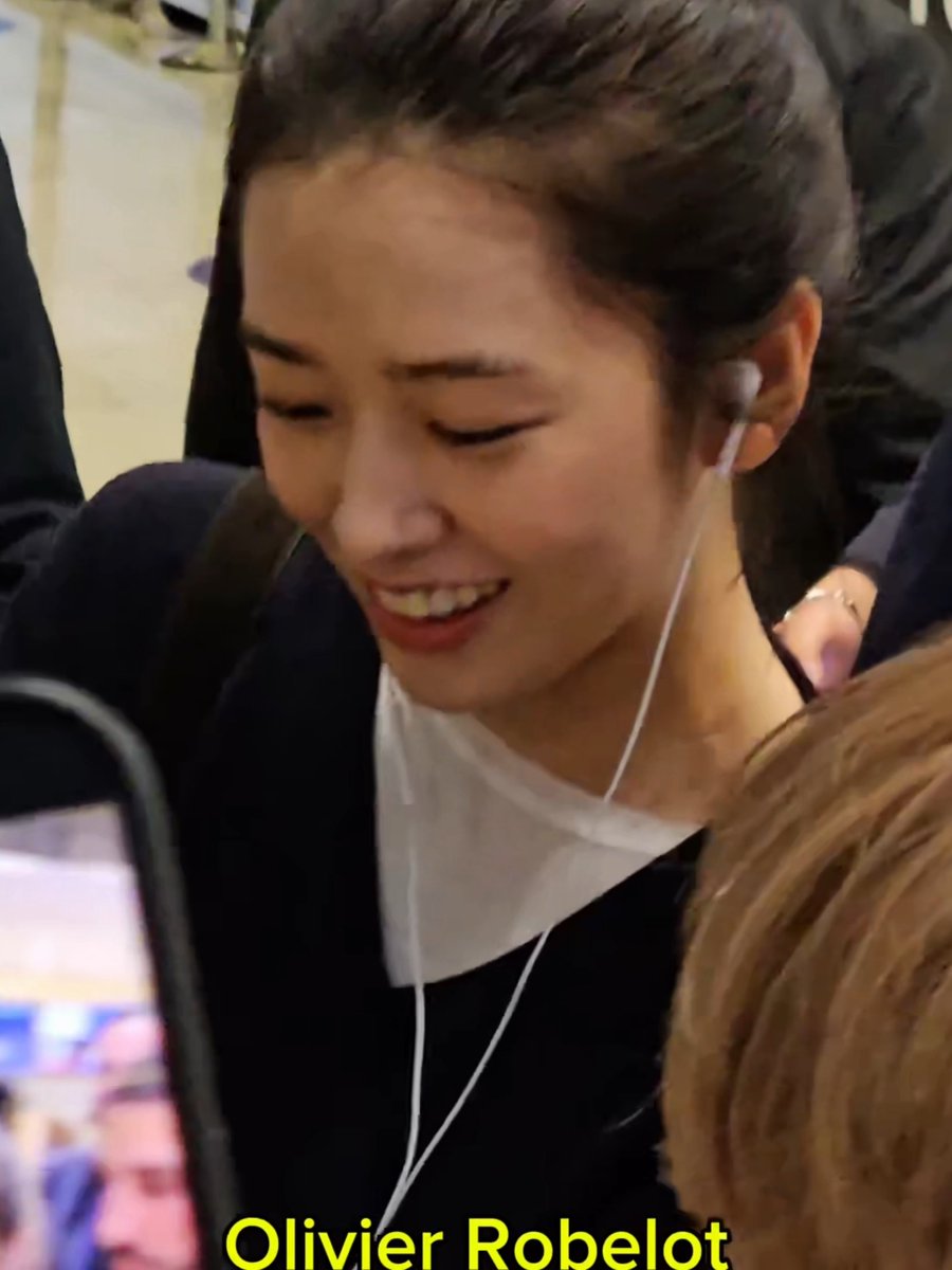 A close-up photo of a smiling young woman with dark hair wearing earphones, looking down, with the name "Olivier Robelot" overlaid in yellow text at the bottom.